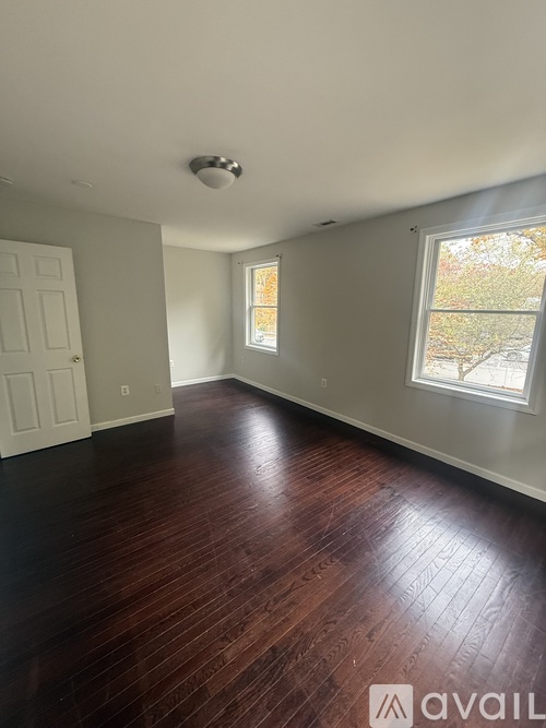 A room with wooden floors and a window showing trees outside.