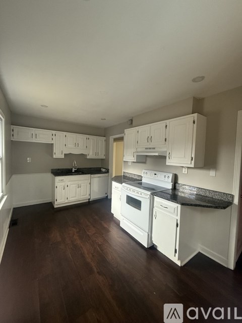 A kitchen with white cabinets and black countertops.