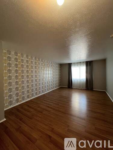 A room with wooden floors and a wallpapered wall.
