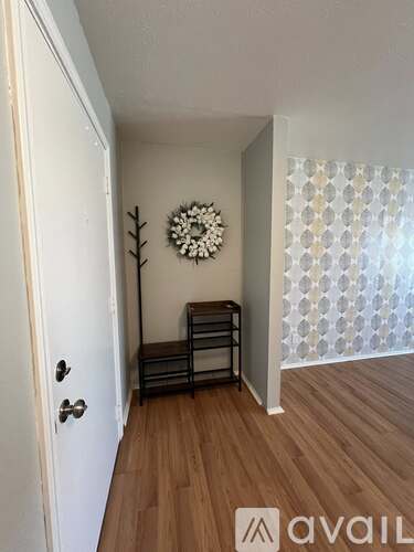 A hallway with a door, a bench, and a wall hanging.