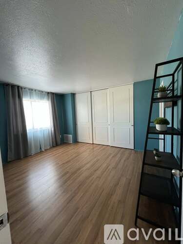 A room with wooden flooring and a ladder against the wall.