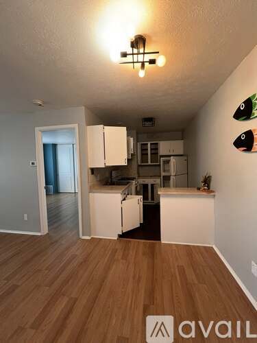 A kitchen area with white cabinets and a wooden floor.