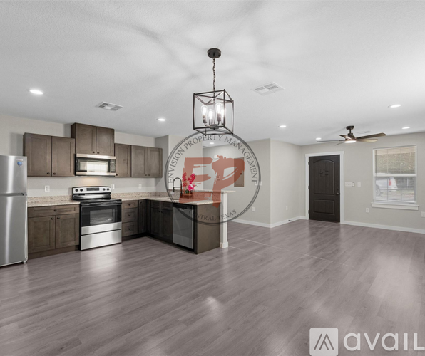 A modern kitchen with wooden floors and stainless steel appliances.