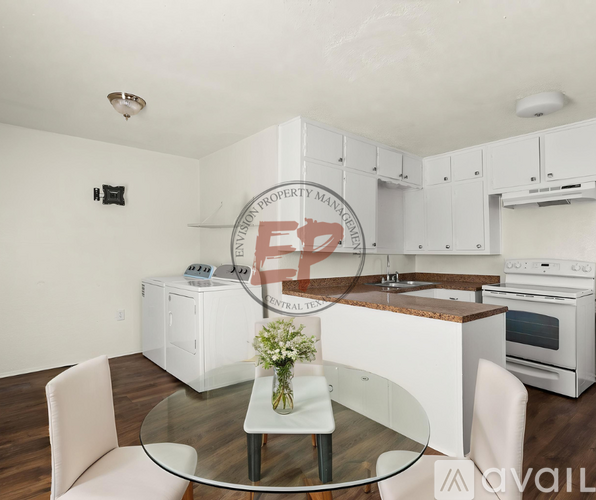 A modern kitchen with white cabinets and a glass table.