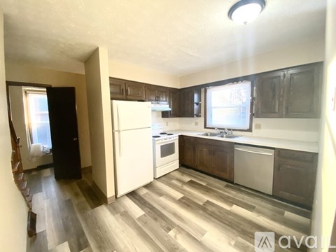 A kitchen with wooden floors and white appliances.