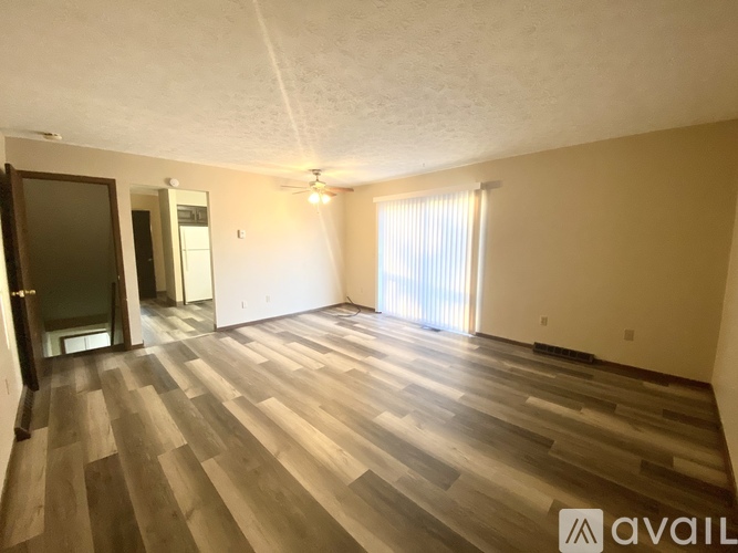 A spacious room with wooden flooring and a ceiling fan.