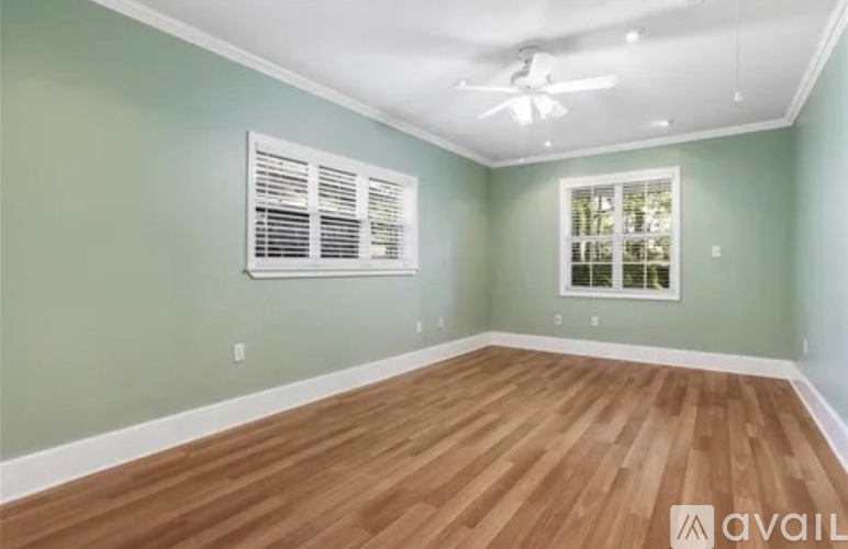 A room with wooden flooring and a window with blinds.