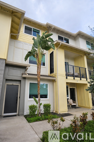 A yellow and white apartment building with a palm tree in front.