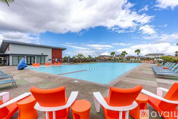 A pool area with orange chairs and a building in the background.