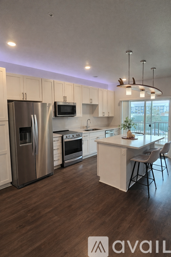 A modern kitchen with wooden floors and stainless steel appliances.