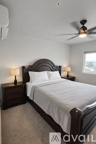 A bedroom with a large bed and two lamps.