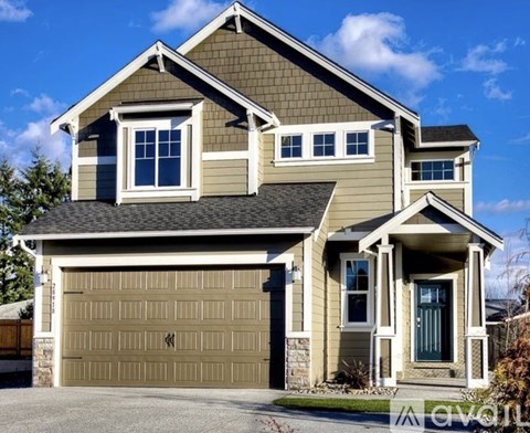 A two-story house with a garage door and a covered porch.