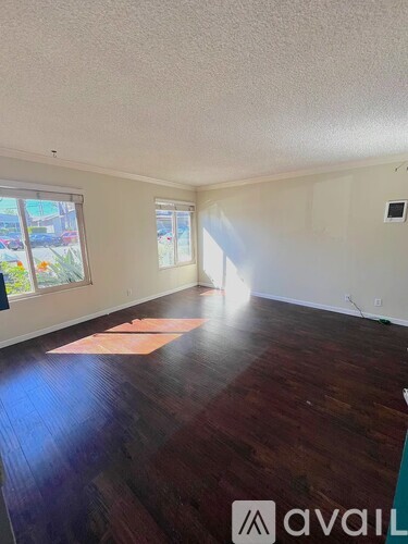 A room with wooden floors and a window letting in sunlight.