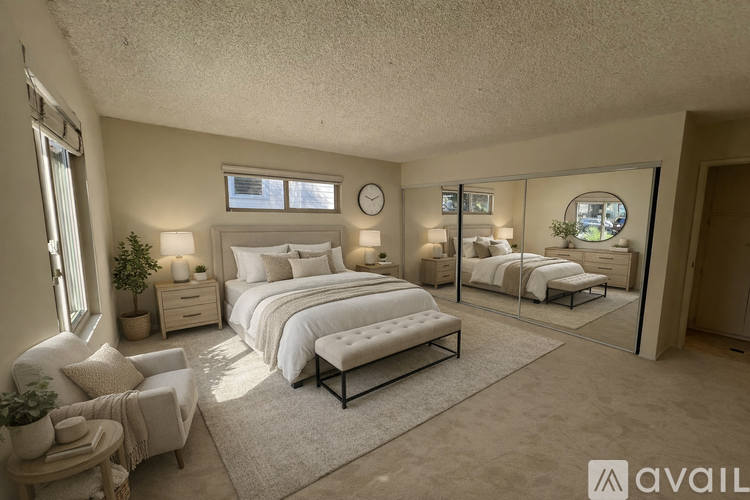 A bedroom with a large bed, a bench, and a mirror on the wall.