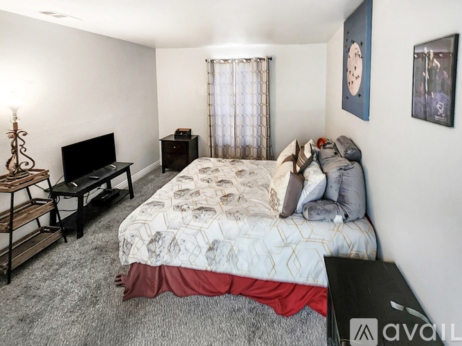 A bedroom with a bed, a television, and a clock on the wall.