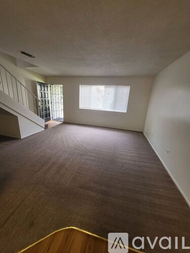 A room with wooden flooring and a window with blinds.