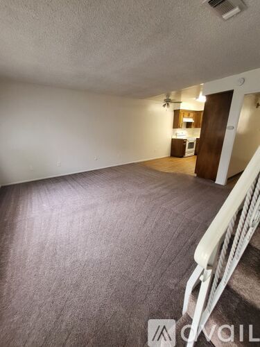 A room with a carpeted floor and a white railing.