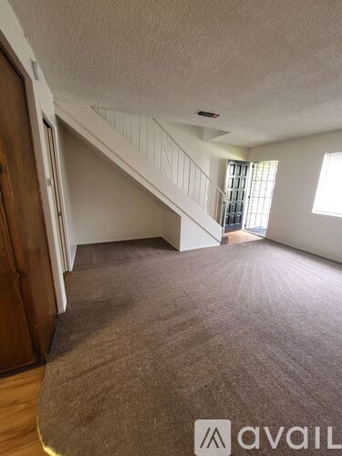 A carpeted room with a staircase leading to another floor.