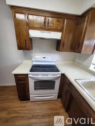 A white stove top oven with a glass window sits under a cabinet in a kitchen.