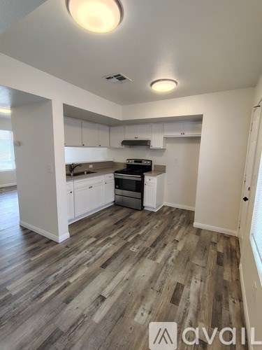 A kitchen with white cabinets and a wooden floor.