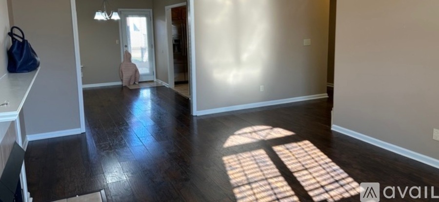 A room with a wooden floor and a window letting in sunlight.