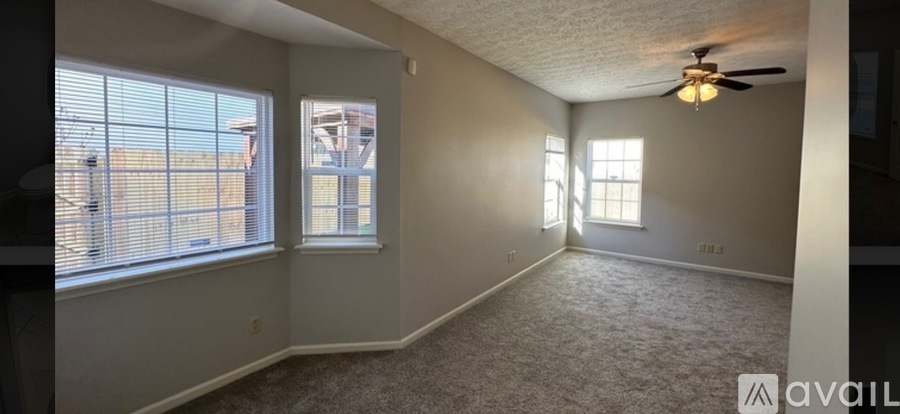 A spacious room with a ceiling fan and two windows.