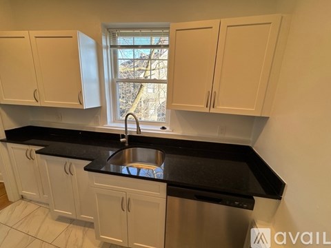 A kitchen with white cabinets and a black countertop.