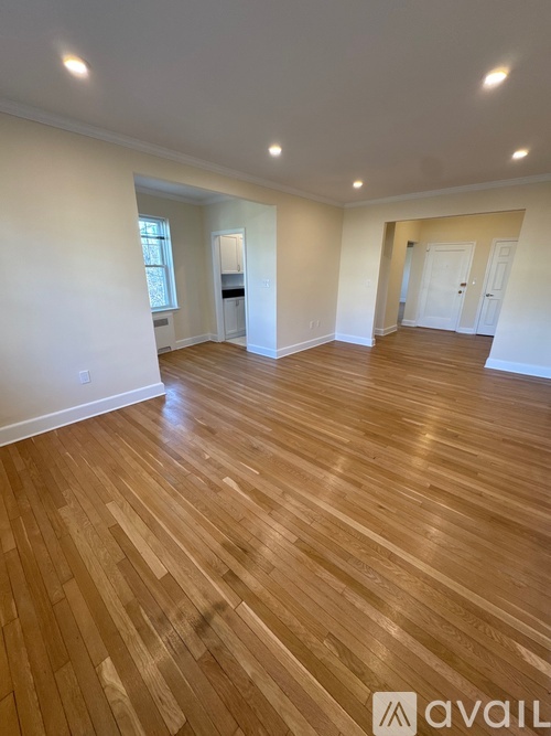 A spacious room with wooden flooring and white walls.