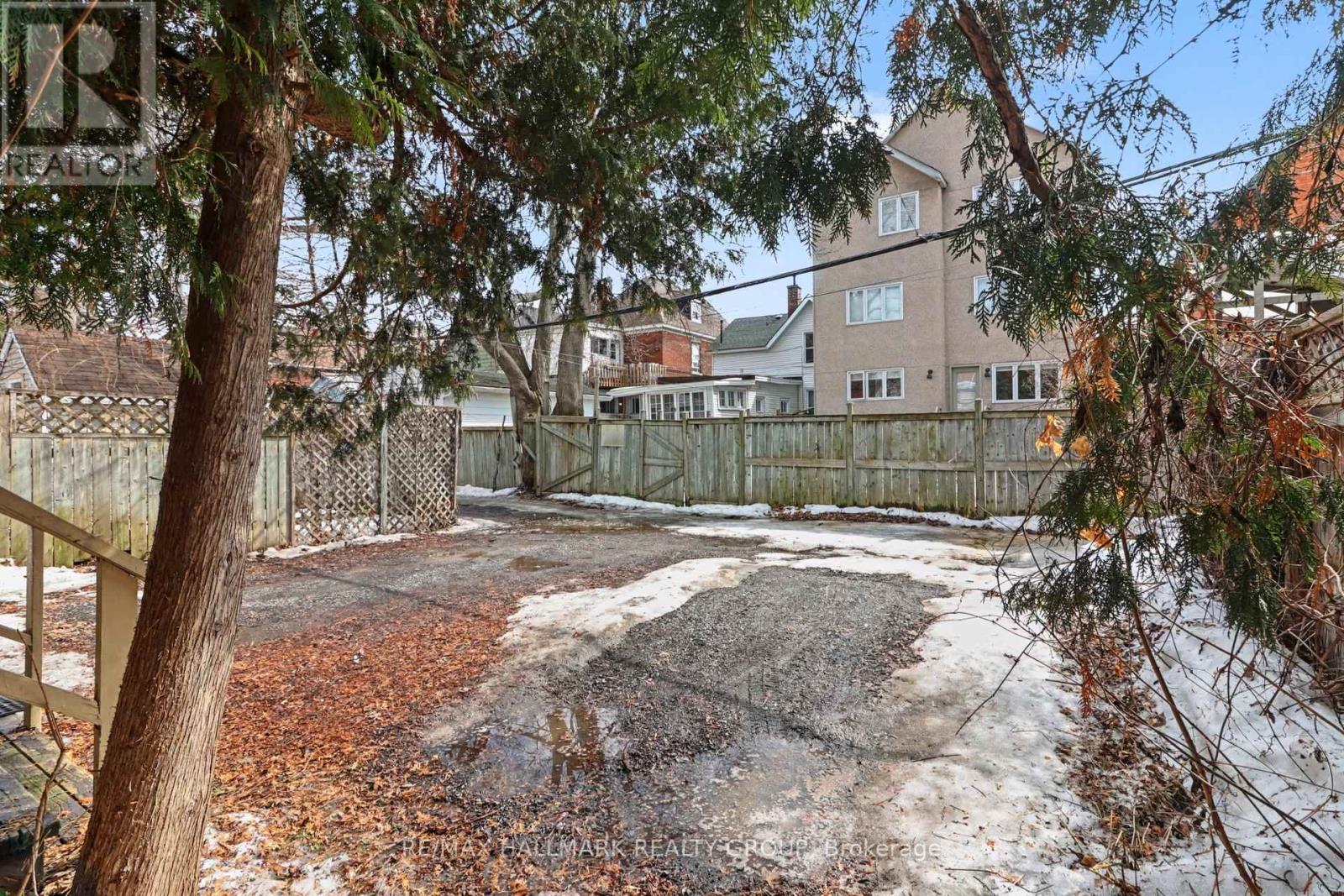 A backyard with a fence, trees, and a building in the background.