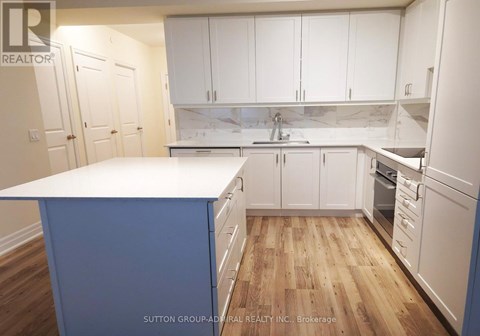 A kitchen with white cabinets and a blue island.