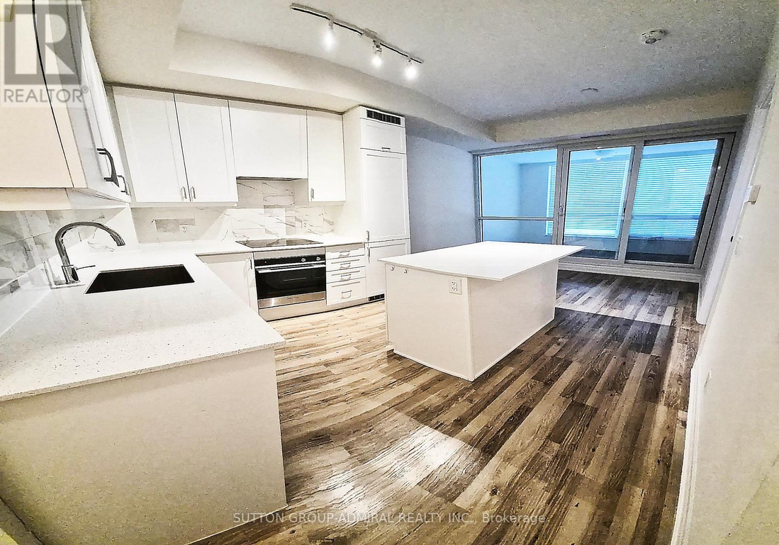 A kitchen with white appliances and wooden floors.