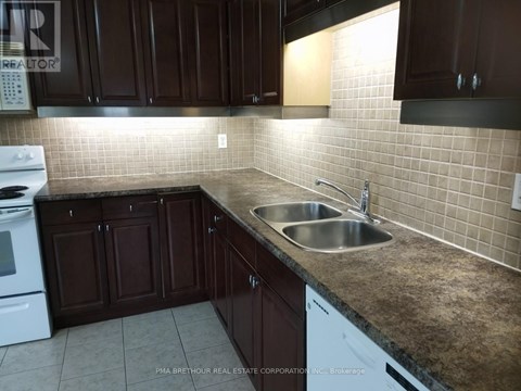 A kitchen with brown cabinets and a white dishwasher.