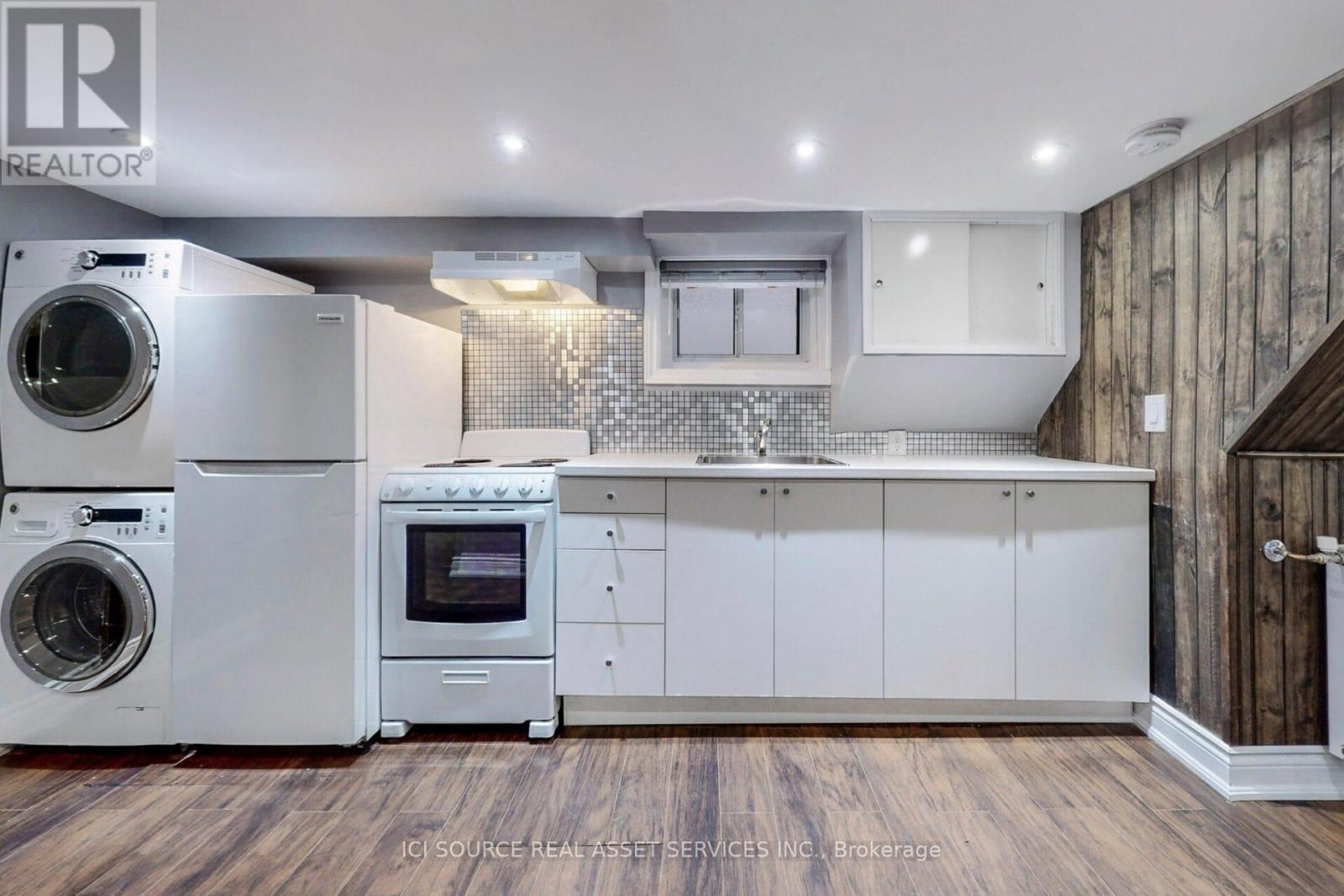 A modern kitchen with white appliances and wooden floors.