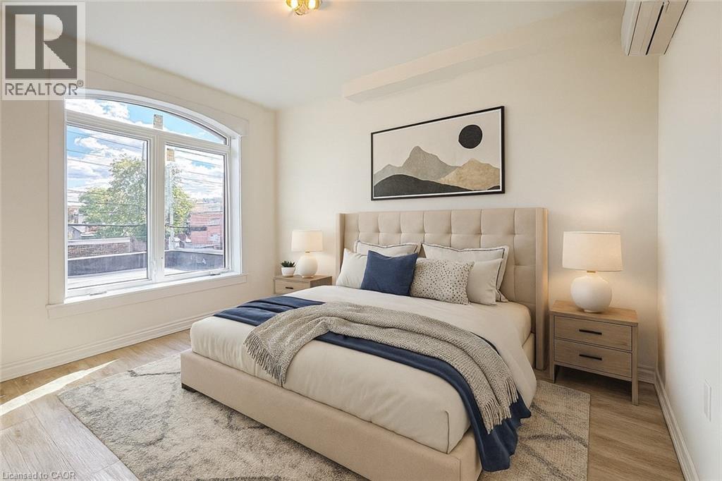 A bedroom with a large bed, a nightstand, and a window.