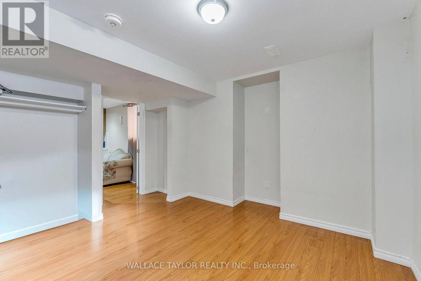 A spacious room with wooden floors and white walls, with a sliding door leading to another room.
