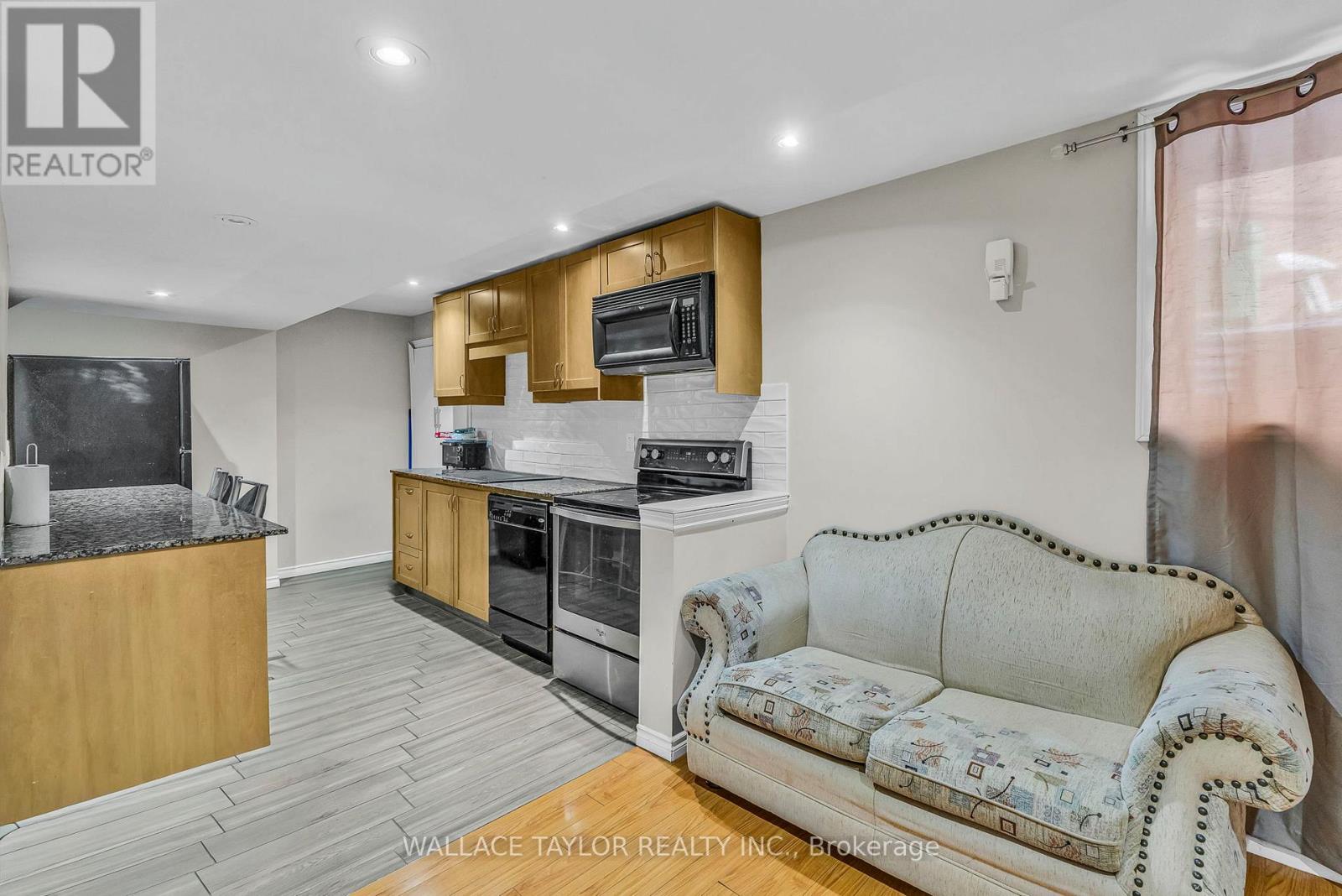 A living room with a couch and a kitchen area in the background.