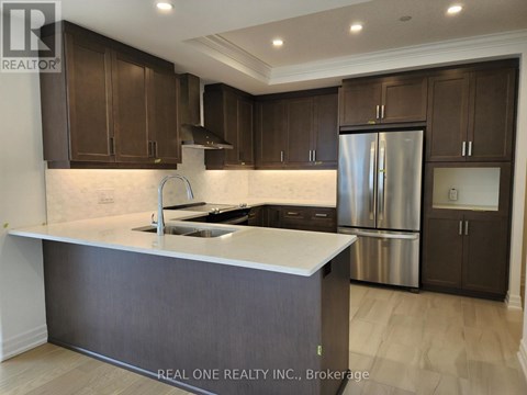 A modern kitchen with dark brown cabinets and a stainless steel refrigerator.