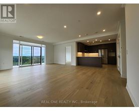 A spacious room with wooden flooring and a large window overlooking a landscape.