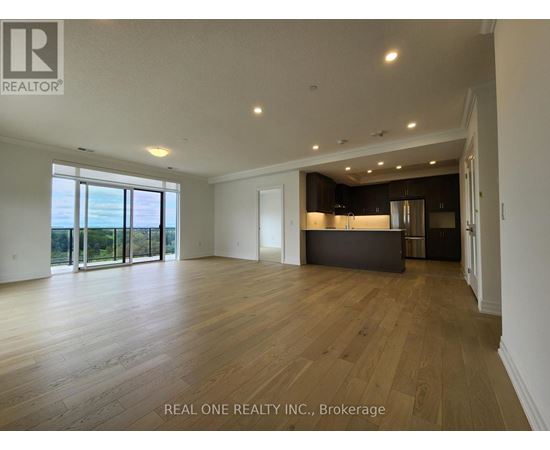 A spacious room with wooden flooring and a large window overlooking a landscape.