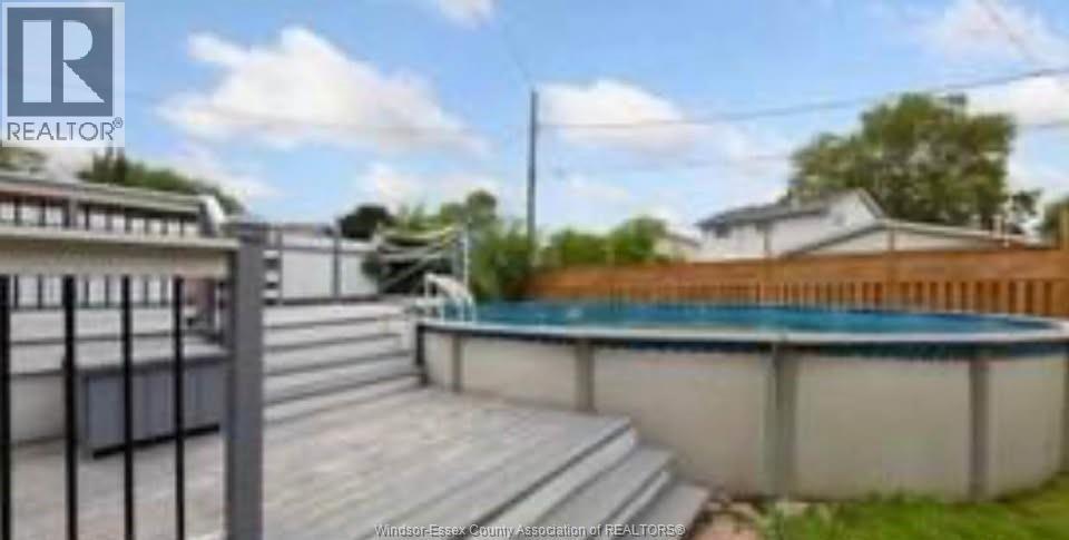 A pool with a deck and a fence in the background.