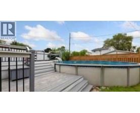 A pool with a deck and a fence in the background.