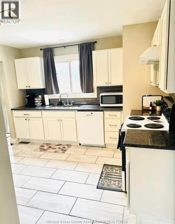 A kitchen with white cabinets and a black countertop.
