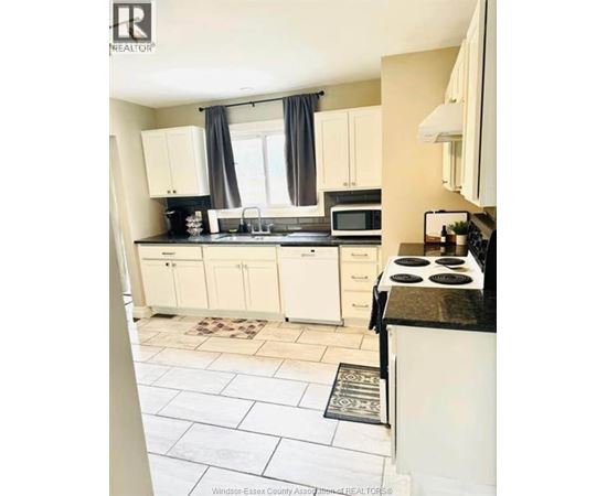 A kitchen with white cabinets and a black countertop.