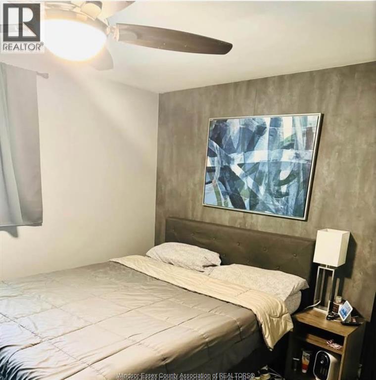 A bedroom with a bed, nightstand, and a painting on the wall.