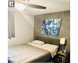 A bedroom with a bed, nightstand, and a painting on the wall.