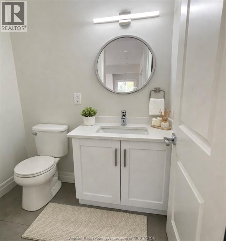 A white bathroom with a toilet, sink, and mirror.