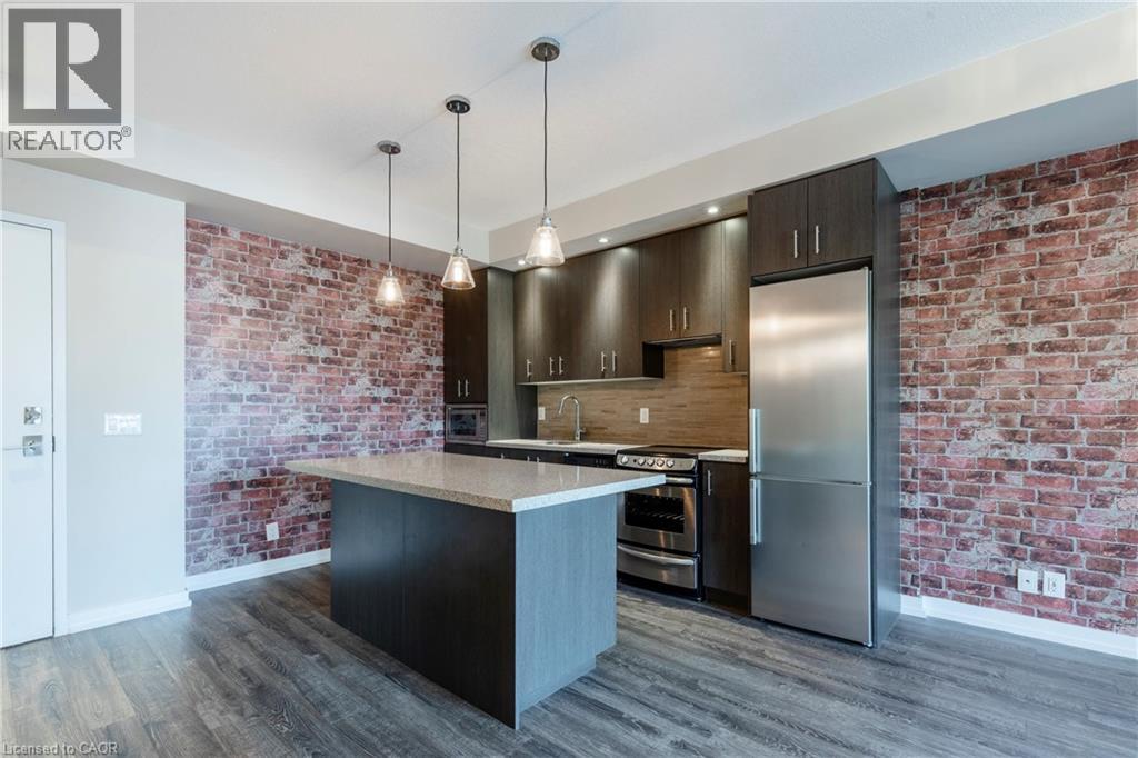 A modern kitchen with a brick wall and stainless steel appliances.