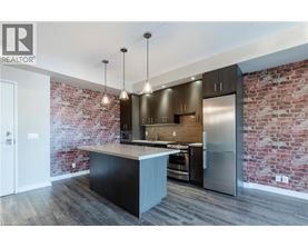 A modern kitchen with a brick wall and stainless steel appliances.