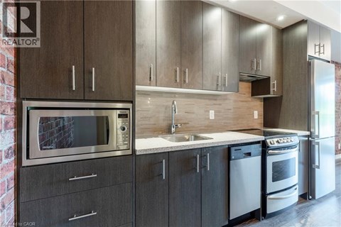 A modern kitchen with dark wood cabinets and stainless steel appliances.