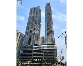 Two tall buildings with glass windows and balconies are shown in the image.